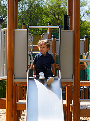 Boy is preparing to slide down on a playground play system.